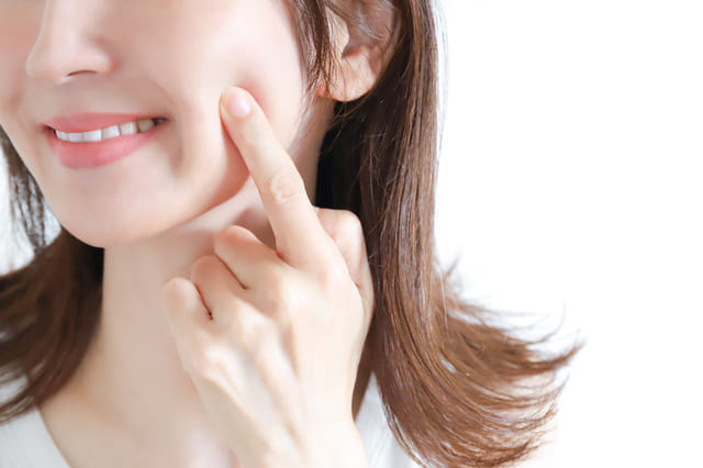 頬に手を当てて肌の状態を確認する女性