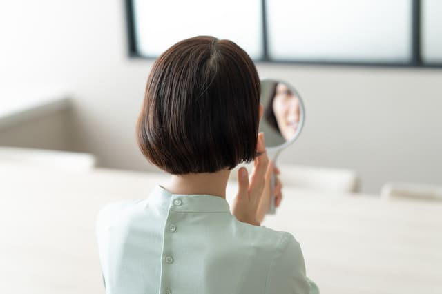 鏡を見ながら肌の状態をチェックする女性