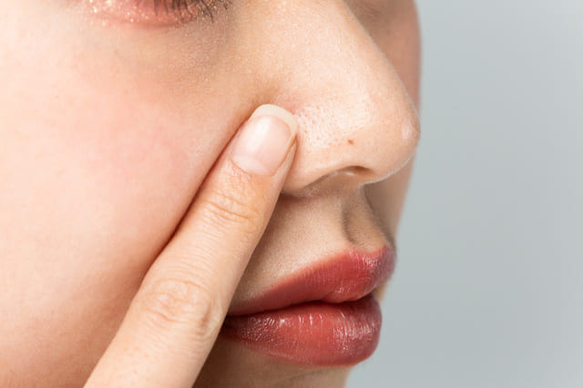 鼻の毛穴を気にして触れる女性のアップ