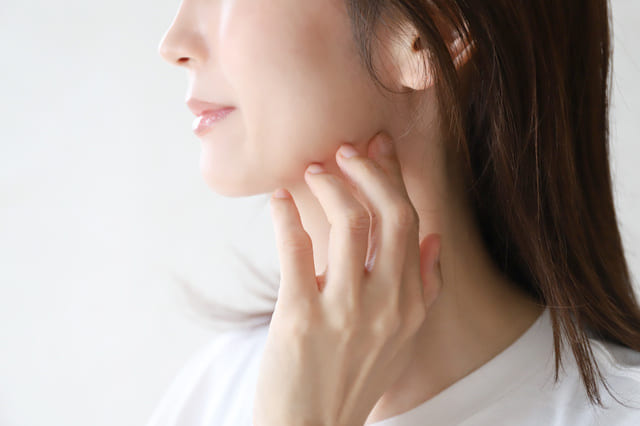 女性が頬に手を添えて肌の状態を確認している様子