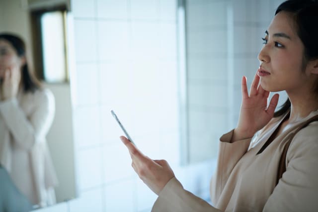 鏡の前で肌の状態を確認する女性