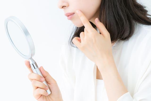 鏡を見ながら肌の状態を確認する女性