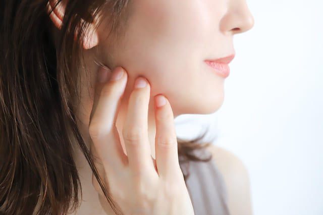 頬に手を当てて保湿ケアをする女性