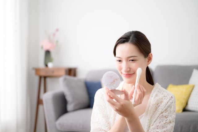 鏡を見ながらチークを塗る女性