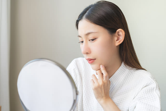 鏡を見ながら肌の状態をチェックする女性