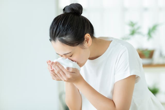 鏡を見ながら顔を洗う女性