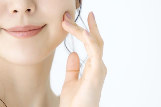 頬に指を触れる女性の顔のアップ