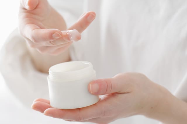 スキンケア用クリームを容器から手に取る様子