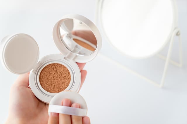 鏡の前でクッションファンデーションを使う様子