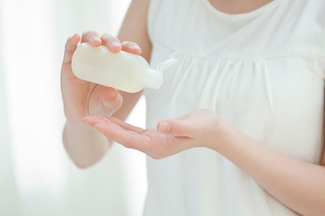 手のひらに化粧水を取ってスキンケアをする女性