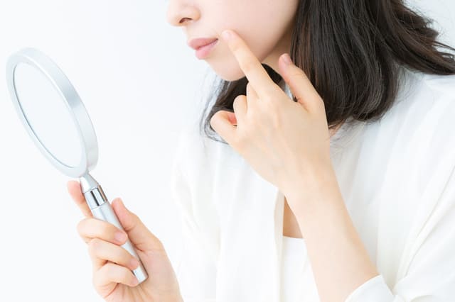 手鏡で肌を確認する女性