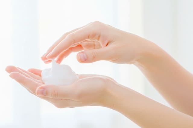手のひらに化粧水を取る女性の手元