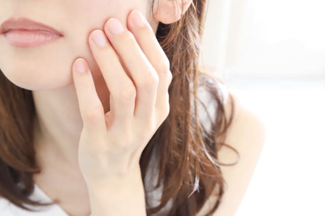 頬に触れる女性の口元のアップ写真