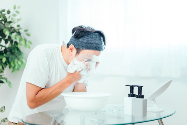 洗顔フォームを泡立てて顔を洗う男性