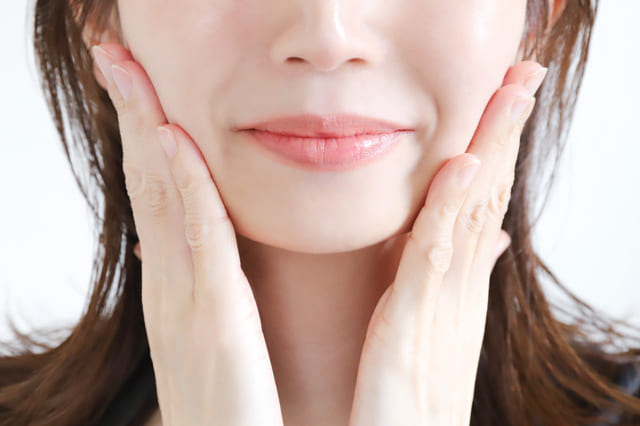 両手で頬を包み込むようにスキンケアする女性