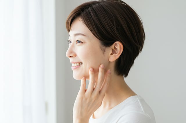 鏡を見ながらスキンケアをする女性