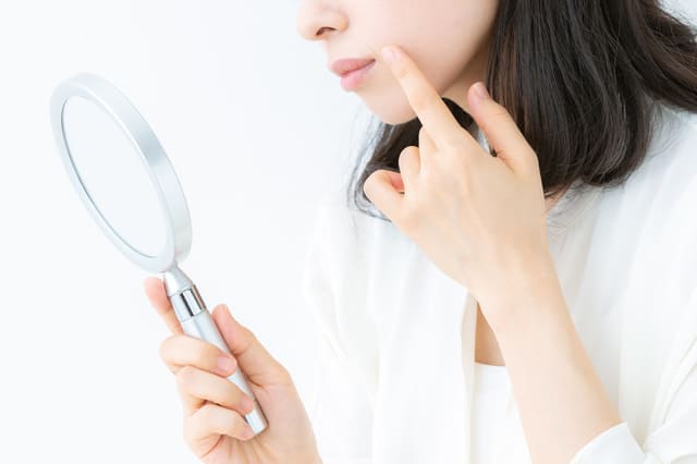 鏡を見ながら肌の状態を確認する女性