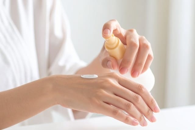 手の甲にスキンケアクリームをなじませる女性