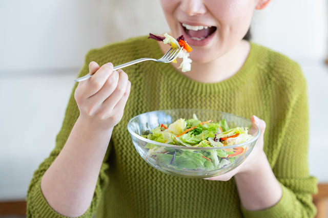 サラダを口に運んでいる女性