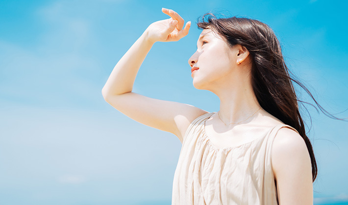 眩しそうに太陽を見る女性