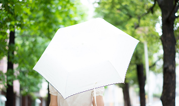 おでこ乾燥を防ぐために日傘をさす女性
