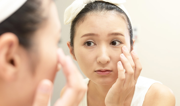 目の周りのくすみや色素沈着を鏡でチェックする女性