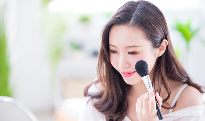 フェイスパウダーをブラシでのせる女性