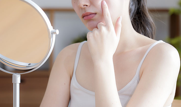 肌ザラザラを鏡で確認する女性