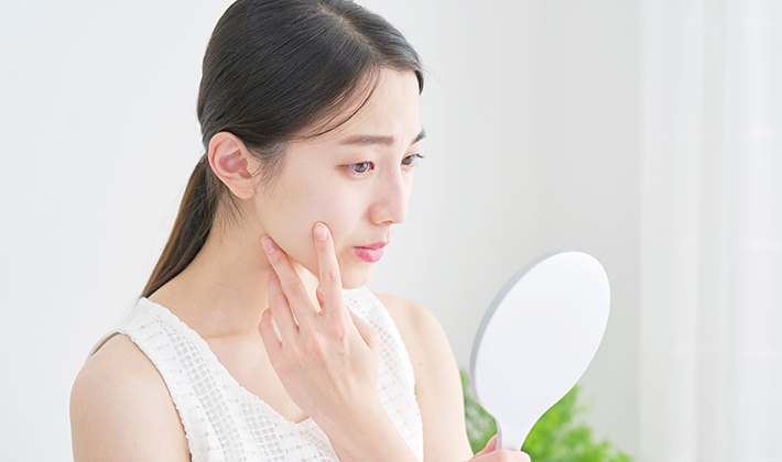 頬に手をあて化粧ノリが悪いことを悩む女性