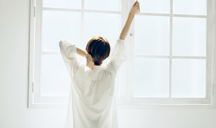 夏の肌荒れを改善し伸びをする女性